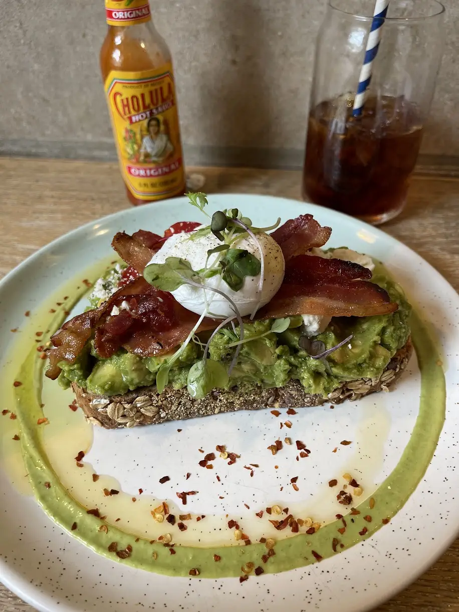 Avocado toast on seeded multigrain with bacon, a poached egg, feta, microgreens and chili flakes
