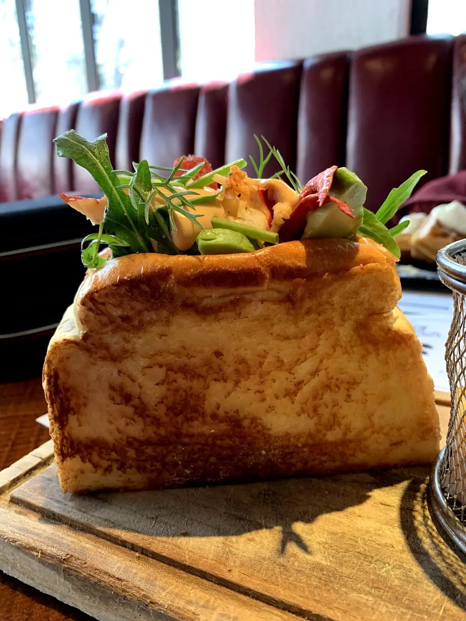 The same toasted bread box from the side, lobster and greens spilling over the top
